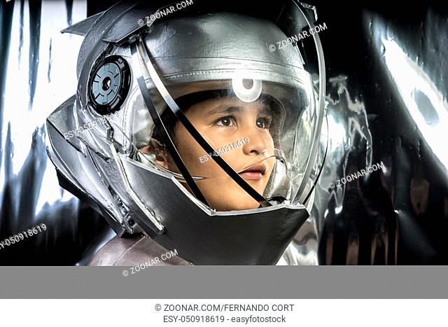 Future, Boy playing to be an astronaut with a space helmet and silver suit on metallic background