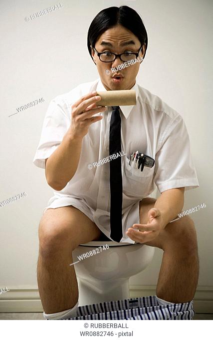 Close-up of a young man sitting on a toilet