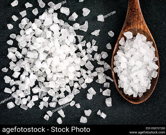 coarse sea salt in spoon on stone close up. Copy space. Flat lay or top view
