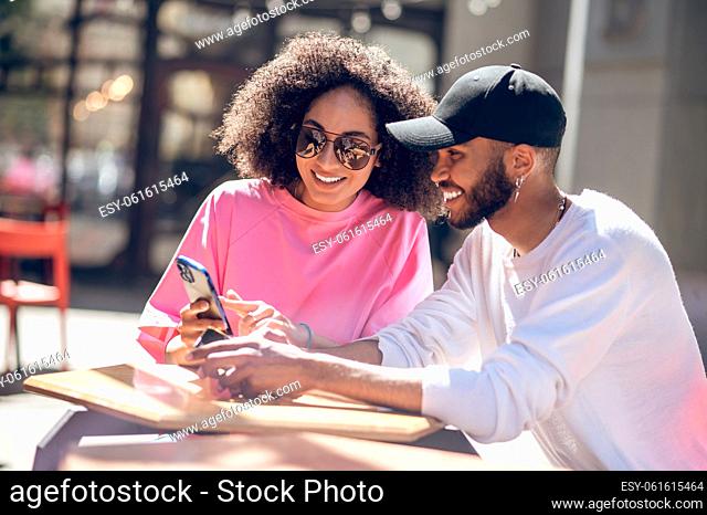 Enjoying together. Young cute couple sitting together and watching something on internet