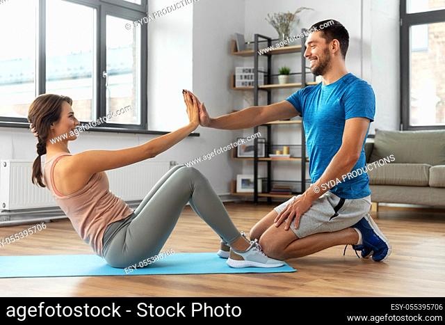 woman with personal trainer doing sit ups at home