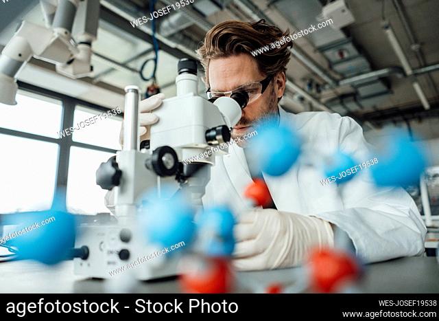 Scientist examining with microscope in laboratory
