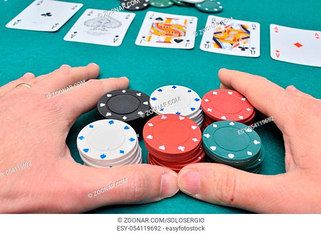 Stack of poker chips in two hands and cards on a gambling table with chips