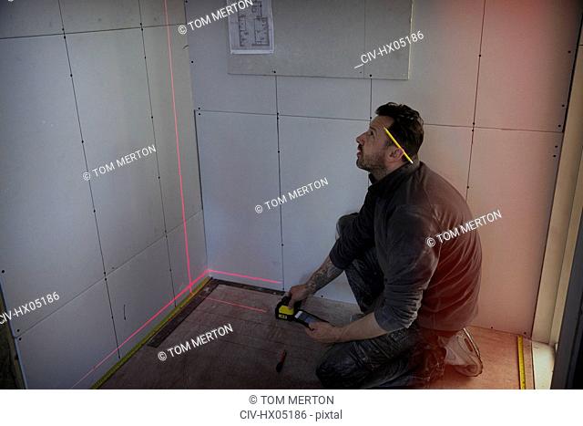 Construction worker using laser measuring tool