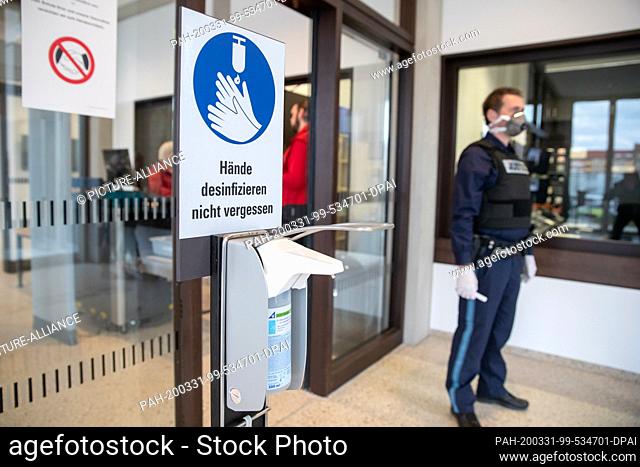 31 March 2020, Bavaria, Nuremberg: ""Don't forget to disinfect your hands"" is written above a dispenser with disinfectant in the entrance area of the...