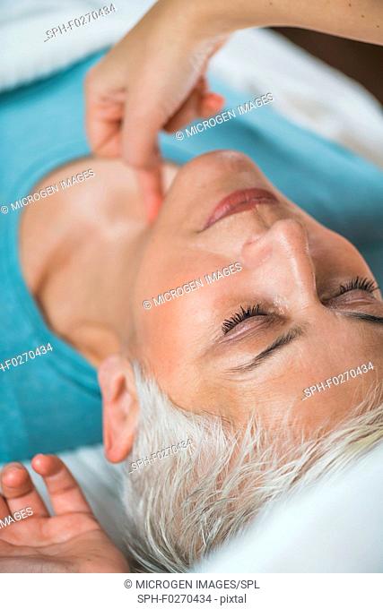Marma therapy. Senior woman lying on massage table and enjoying Ayurveda neck treatment. Kanth Marma