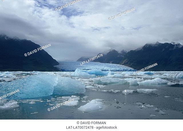 Parque nacional Laguna San Rafael. Iceberg/ blue transluscent ice in sea. End of glacier. Hills