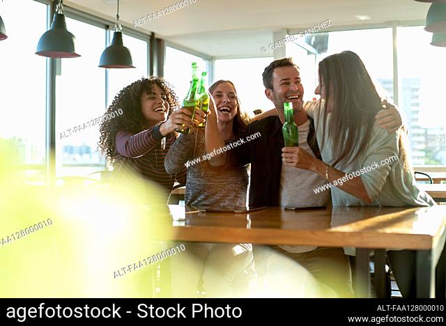 Smiling colleagues toasting drink bottles in office