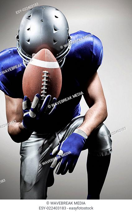 Composite image of upset american football player kneeling while holding ball