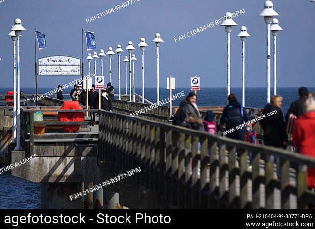 04 April 2021, Mecklenburg-Western Pomerania, Ahlbeck: Strollers walk on the pier of Zinnowitz on the island of Usedom on Easter Sunday