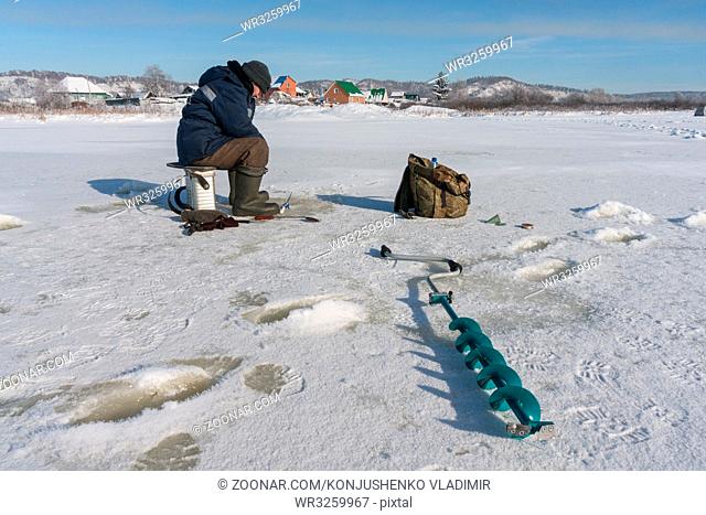 Winter fisherman on the river ice