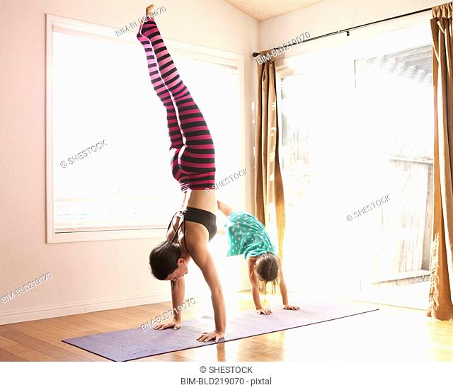 Mother and daughter practicing yoga in studio