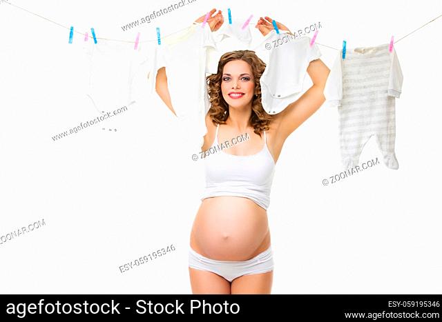 Beautiful pregnant young woman holding kids clothes