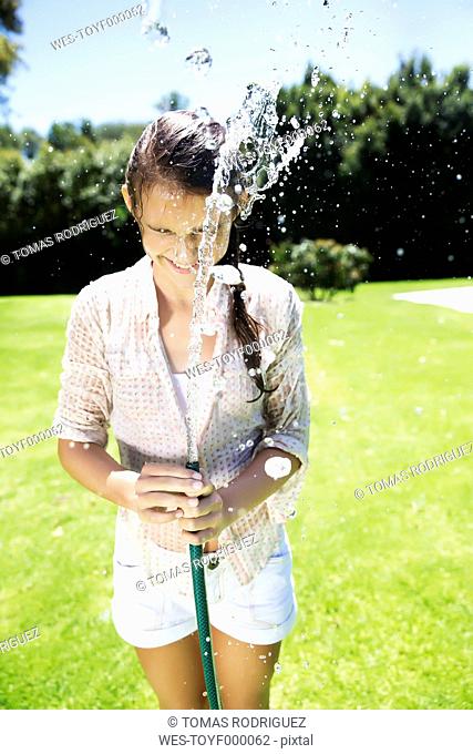 Young girl splashing water with garden hose