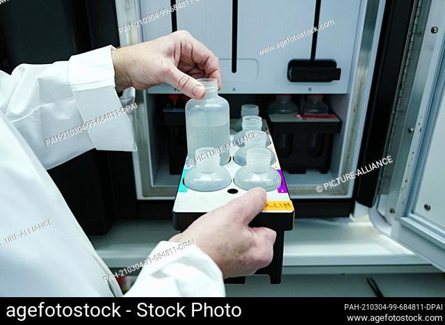 04 March 2021, Baden-Wuerttemberg, Heidelberg: An employee takes a container from a cabinet in a sequencing laboratory at the European Molecular Biology...