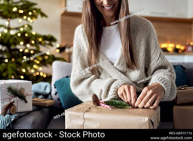 Smiling woman wrapping gift at home