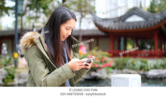Woman playing game on cellphone at china, Chinese pavilion garden