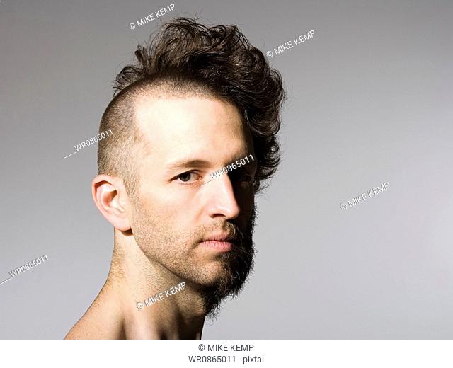 Shirtless man with half shaved hair and beard