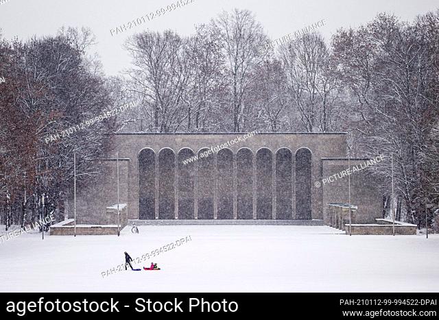 12 January 2021, Bavaria, Nuremberg: Adults and children enjoy the winter weather in the Luitpoldhain park. The Hall of Honour can be seen in the background