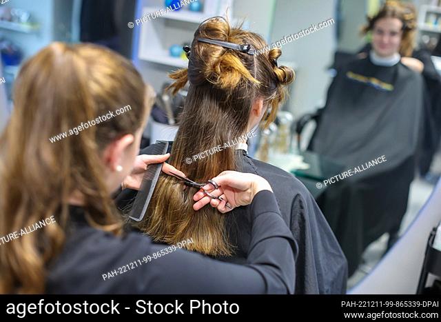 08 December 2022, Saxony-Anhalt, Wettin-Löbejün: A hairdresser cuts the hair of a customer in a salon. The 21-year-old will take over her grandmother's salon in...