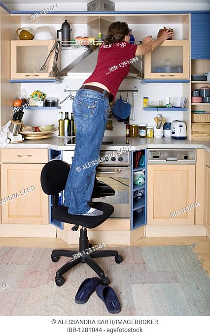 Household accident, girl standing on a swivel chair in the kitchen