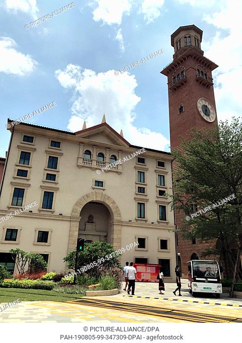 28 June 2019, China, Dongguan: Huawei employees walk in front of a replica of the Torre dei Lamberti tower in Verona, Italy, on the Ox Horn campus