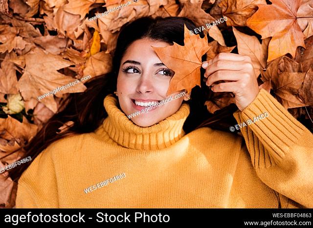 Smiling woman holding dry maple leaf