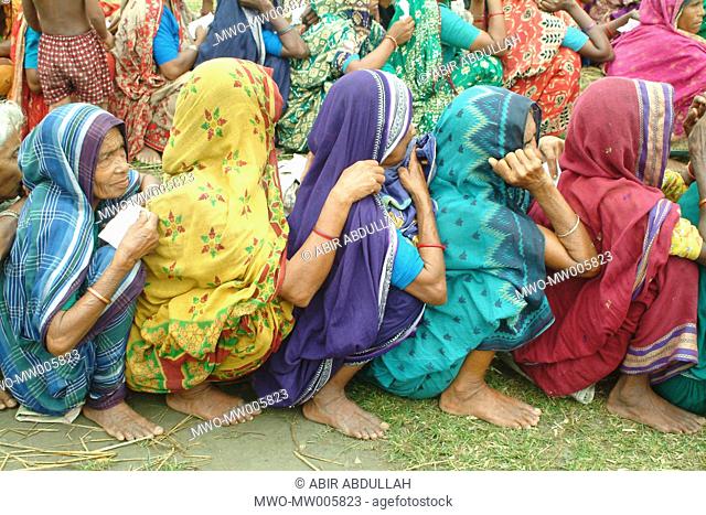 Flood affected women waiting in a que with paper for flood relief Gaibandha, Bangladesh July 21, 2004