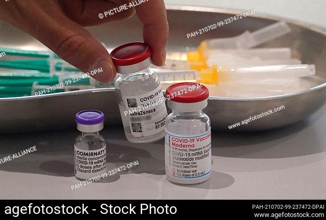 02 July 2021, Hamburg: An employee of the vaccination center in the exhibition halls takes a vaccine can from the Astrazeneca vaccine from the table