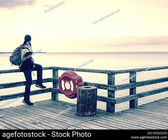 Man traveler on the end of pier watch the far horizon. Moody morning at sea bridge