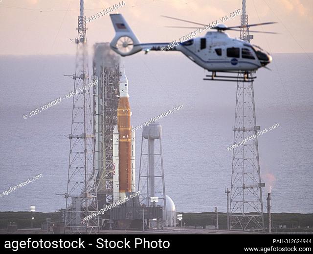 A NASA helicopter flies past the agency’s Space Launch System (SLS) rocket with the Orion spacecraft aboard atop the mobile launcher at Launch Pad 39B, Monday