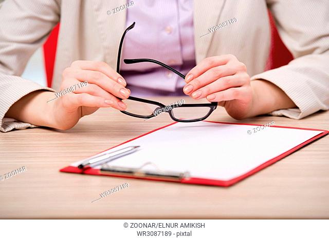 Hand holding glasses at the working desk
