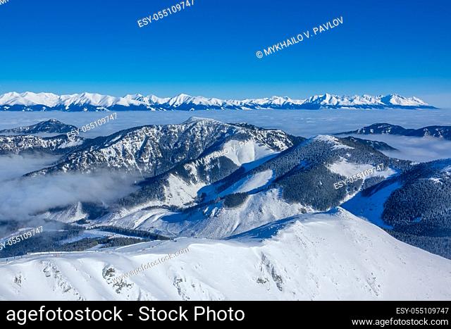 The tops of winter mountains and morning mist in the valleys. Sunny weather and blue sky