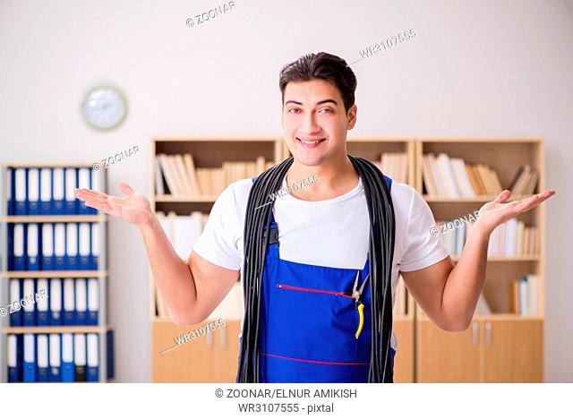 Young electrician with cable working in office
