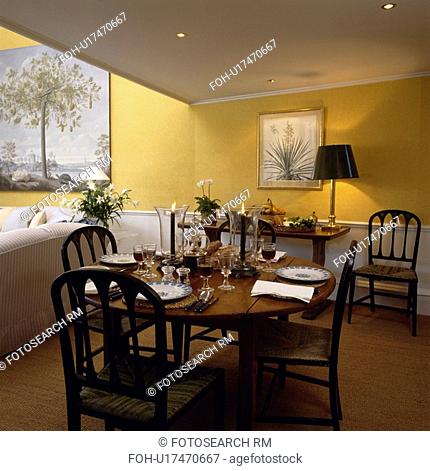 Antique circular table and chairs in yellow eighties dining room with sisal carpet