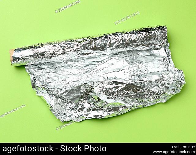 roll of gray foil for baking and packaging food on a green background, top view