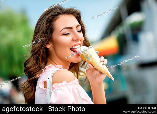 young smiling woman eating ice cream in an amusement park