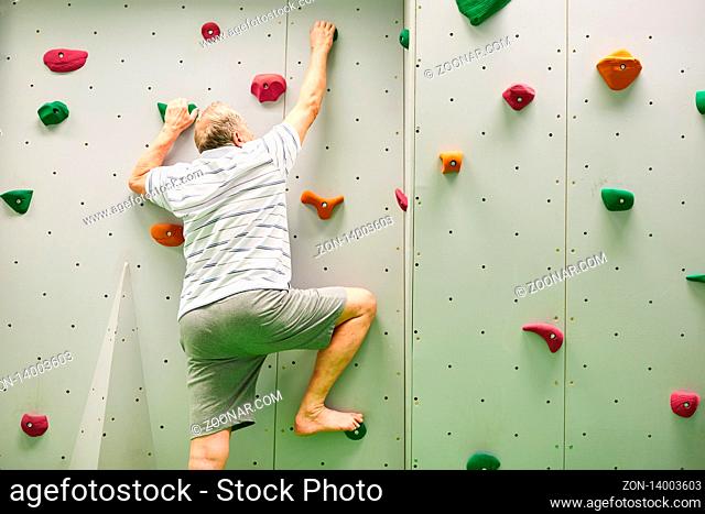 Aktiver Senior Mann beim Klettern in einer Kletterhalle als Fitnesstraining