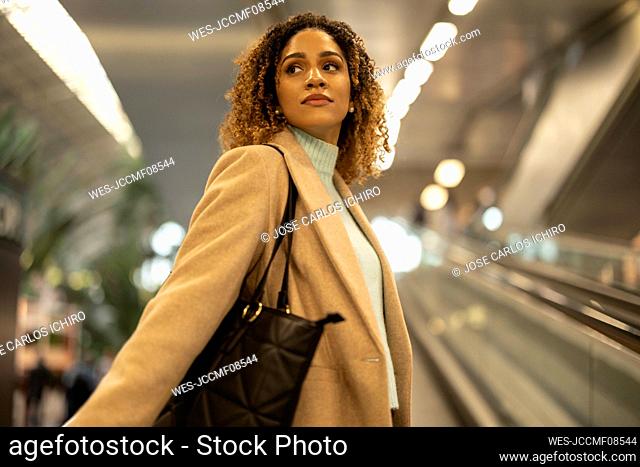 Woman with curly hair on escalator at station