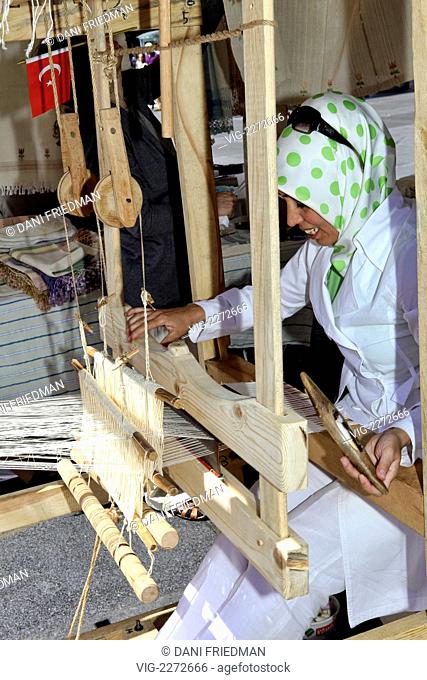 CANADA, TORONTO, 07.08.2010, A Turkish woman weaving on a Dokumacilik (a traditional Turkish loom) making tablecloths and headscarves