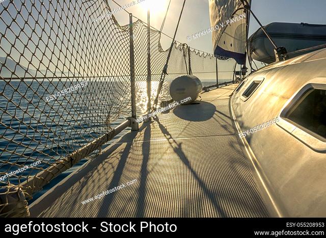 White sailing yacht at sea in calm weather. The staysail is standing. Bright sun backlight
