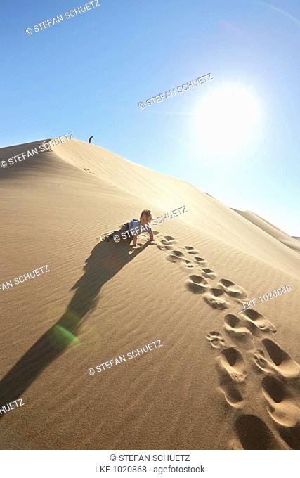 Boy crawling up a sand dune, Dune 7, Walvis Bay, Erongo, Namibia