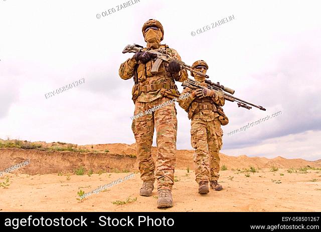 Equipped and armed special forces soldiers with rifles during military operation in the desert