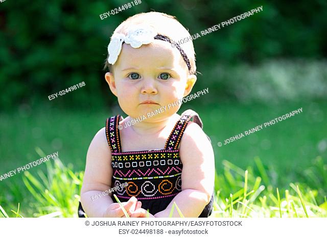 Baby girl at roughly 6 months old outdoors in a natural setting with available light for a lifestyle portrait