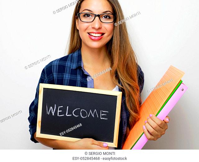 Young female teacher holding folders and blackboard with written welcome