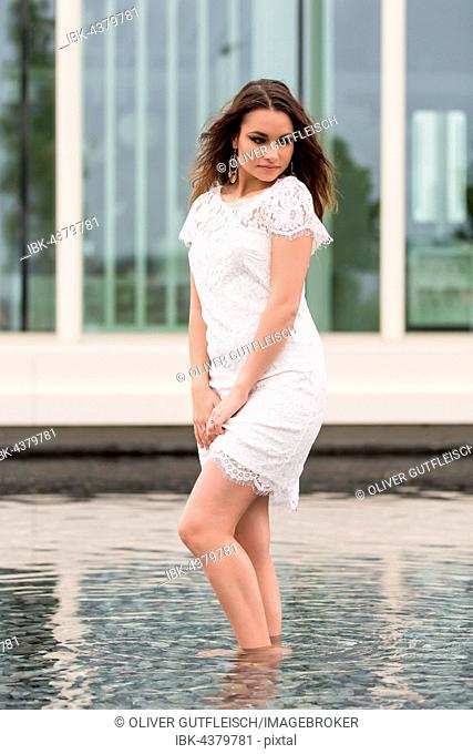 Young woman poses with white summer dress in the water