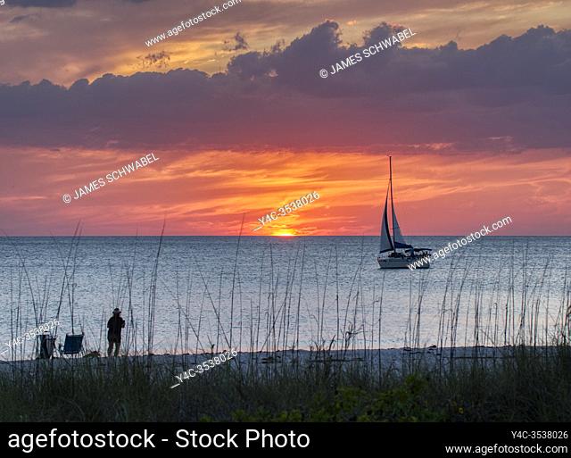 Sailboat in the Gulf of Mexico at sunset with an orange sky off Nokomis Beach ion the Gulf coast of Florida