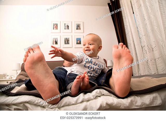 Child playing with the big toe of his father
