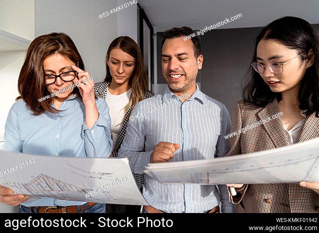 Business people standing in office holding architectural plans