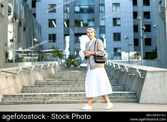 Mature woman walking by steps in city